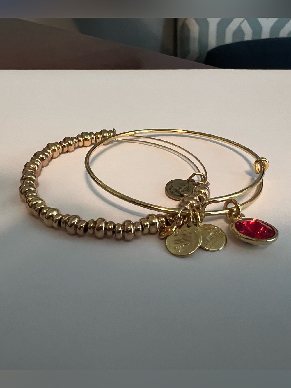 Gold-Tone Stacked Charm Bangle Bracelet with Red Gem Accent
Alex and Ani